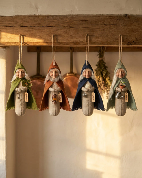 The four Hearth Keepers hanging in a row from an oak beam in a warm farmhouse